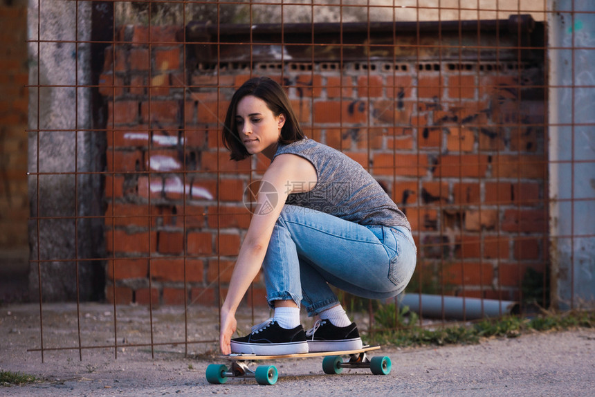 现代的年轻溜冰女青骑在村里长板上穿着散衣自由概念女滑冰图片