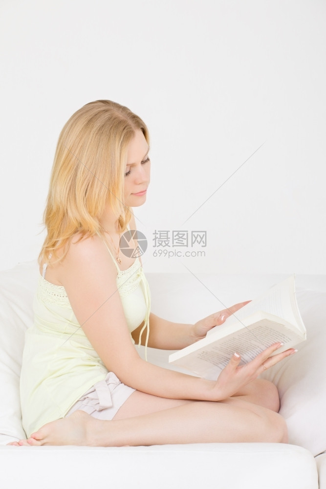 金发在家沙上看书的可爱年轻女孩的赤脚图片