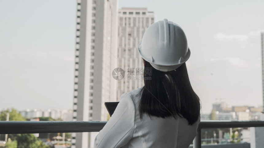 阳光在建筑工地带平板电脑的女建筑工程师戴着白色头盔的自信女建筑师看着工地和概念女户外图片