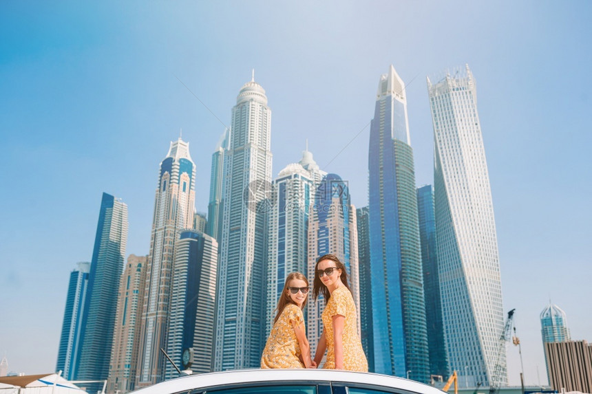 在迪拜摩天大厦背景上度假的妈和小女孩以及年轻家庭度假时旅行的暑期车和青年家庭的背景情况阿拉伯摩天大楼房屋图片