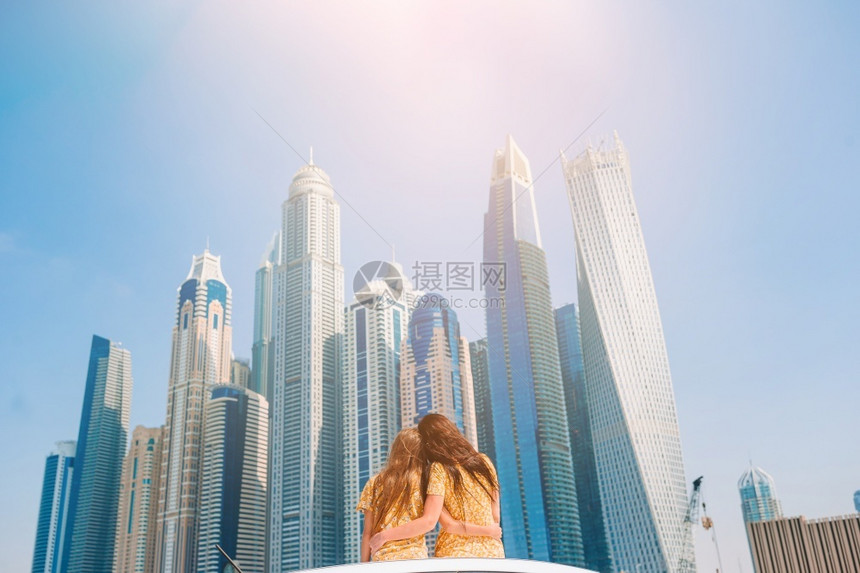 码头在迪拜的摩天大楼背景上度假的母亲和小女孩家庭夏月汽车旅行和青年家庭的假期在迪拜摩天大厦背景上度假年轻的孩子们图片