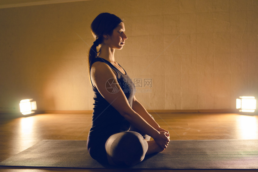 浓度年轻有吸引力的瑜伽女青年在工作室做轻松的座位瑜伽练习平衡身体图片