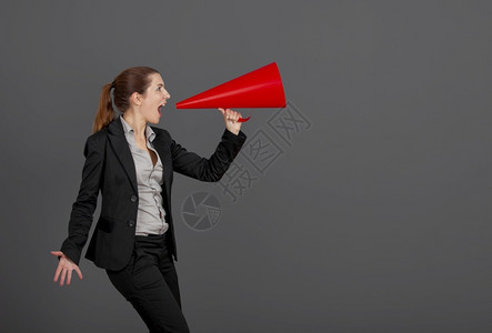 商业女青年在灰色背景下用扩音器说话一种成功消息图片