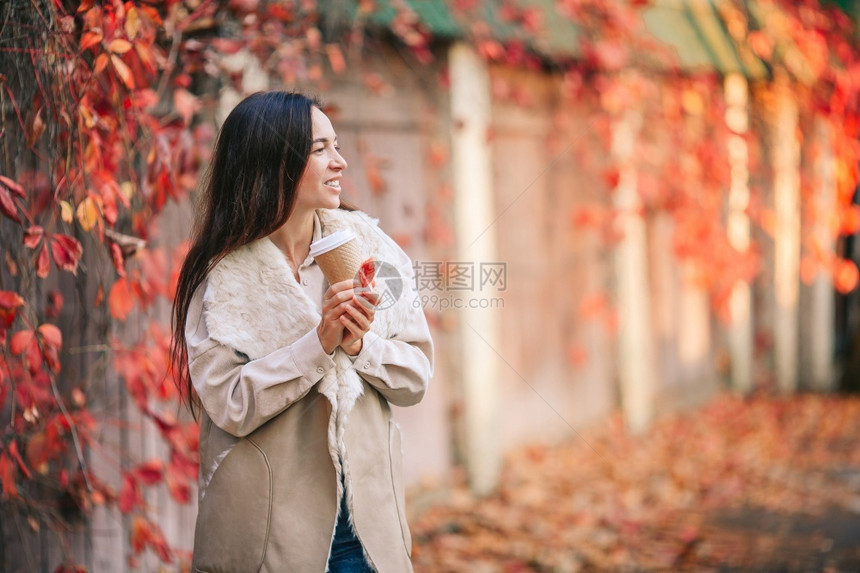 自然摆姿势秋天公园的美丽女子带着咖啡去瀑布概念美丽的女子在秋天公园喝咖啡在秋天树叶下人们图片