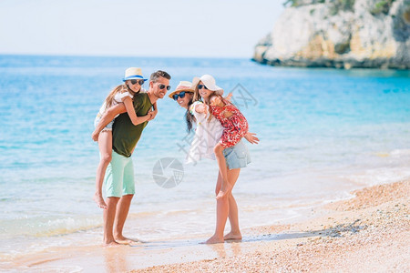 父母给孩子搭便车在海滩上骑马度假的年轻家庭玩得很开心爸横幅女儿图片