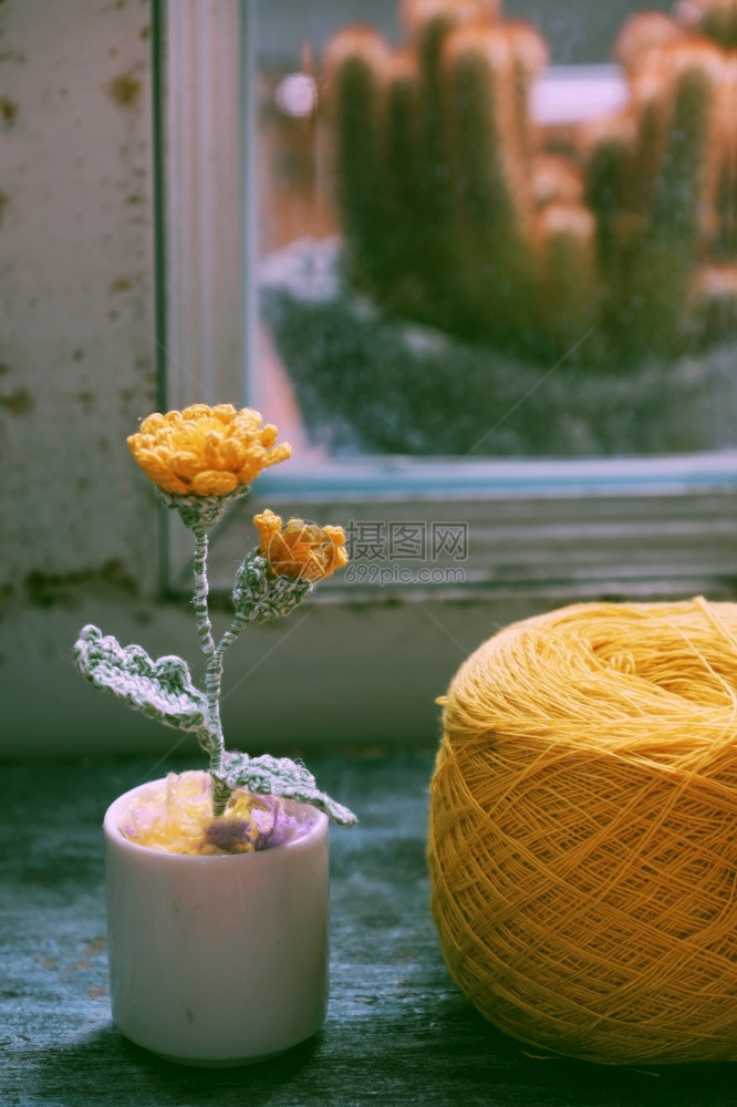 木桌上的编织黄花与毛线球图片
