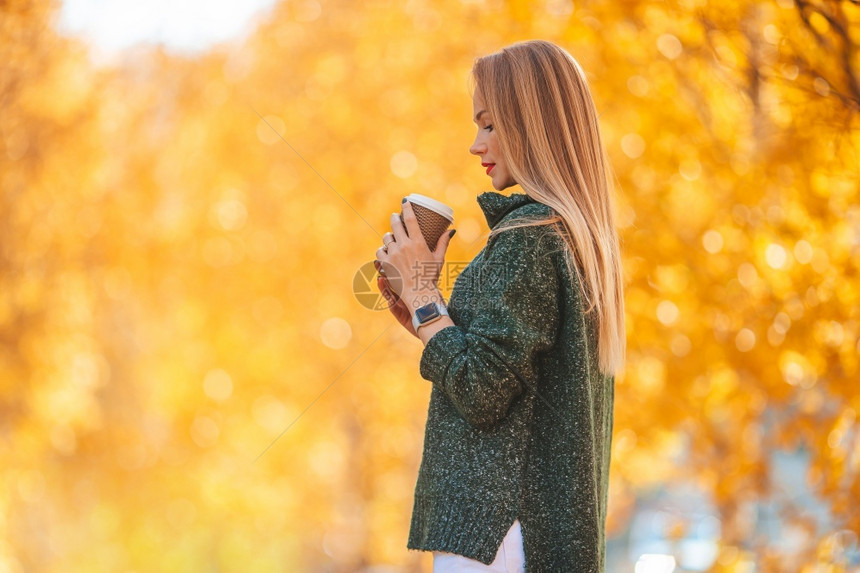 摆姿势黄色的秋天公园漂亮女人带着咖啡去瀑布概念秋天公园喝咖啡的漂亮女人丰富多彩的图片