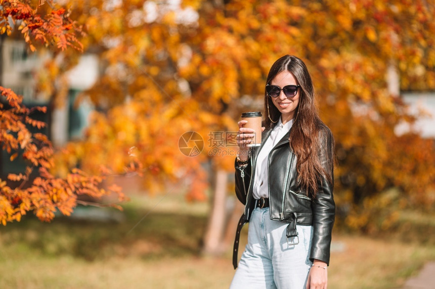 在秋天的落叶下喝咖啡的女人图片