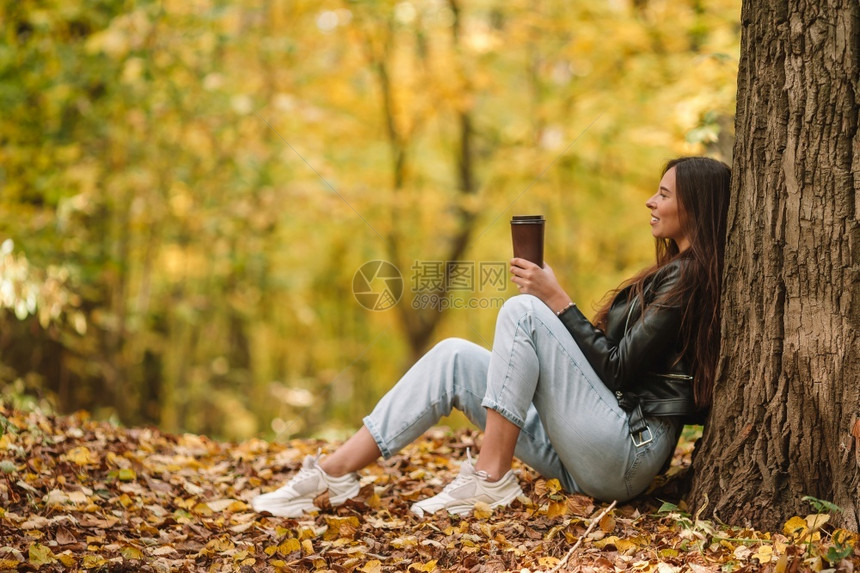 落下华丽的美女人在秋天公园里在温暖的日子里在秋天的落叶下喝咖啡头发图片