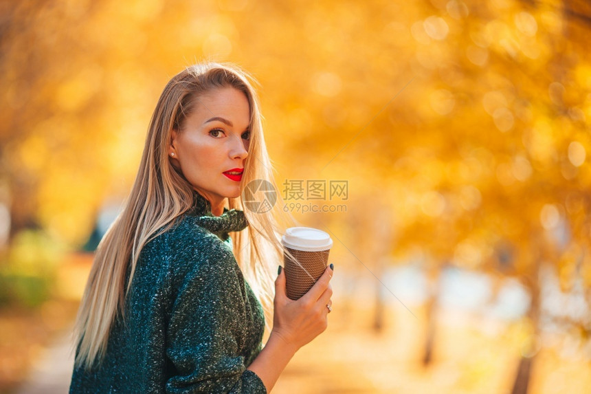 黄色的美丽女人在秋天公园里在温暖的日子里在秋天的落叶下喝咖啡健康森林图片