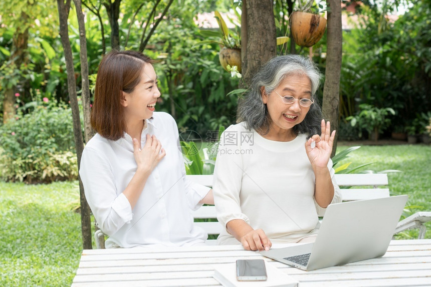 幸福信息年长的退休后学习技术概念和老年人适应改造亚洲女儿教育年长妇使用计算机笔记本电脑手提在线社交媒体教授年长老妇女的亚洲儿图片