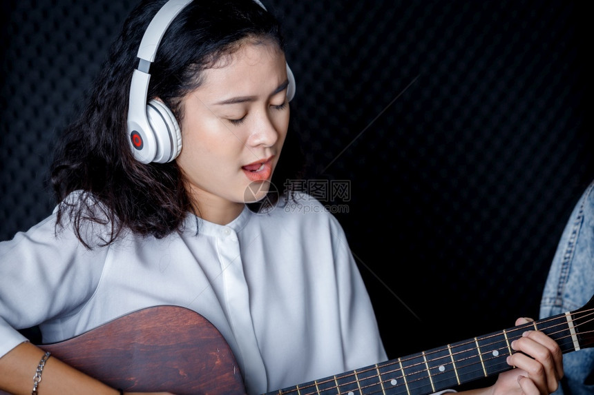 声音记录生产一位年轻的亚洲女歌手戴着耳机在专业工作室录制麦克风前的歌声她笑得很高兴他开心一个年轻的亚洲女发声员戴上耳机图片