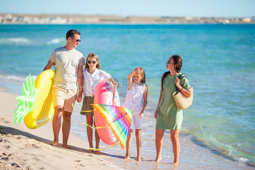 男人准备好父母在海滩上的孩子准备游泳的家长年轻庭度假时玩得开心极了复制图片