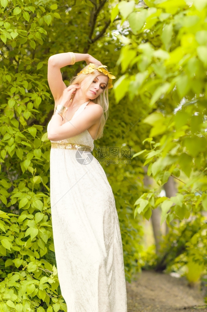 若虫优雅的美丽化妆品女孩身着白色外衣和古董珠宝背景上绿色叶子诱人的图片