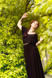 美丽的化妆品女孩身着黑色外衣和古董珠宝背景上绿色叶子魅力吸引人的独自图片