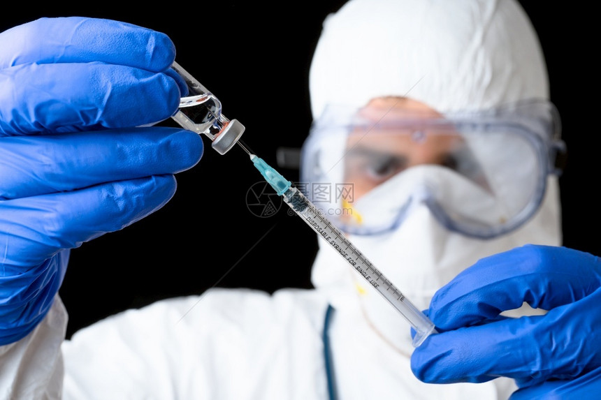 身穿防护服的医生手持疫苗针筒图片