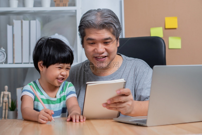 技术在室内亚洲父亲家庭办公室工作手持笔记本电脑教女儿做功课在隔离期间正常的新生活方式住家概念自由职业和父亲概念新生活方式一种图片
