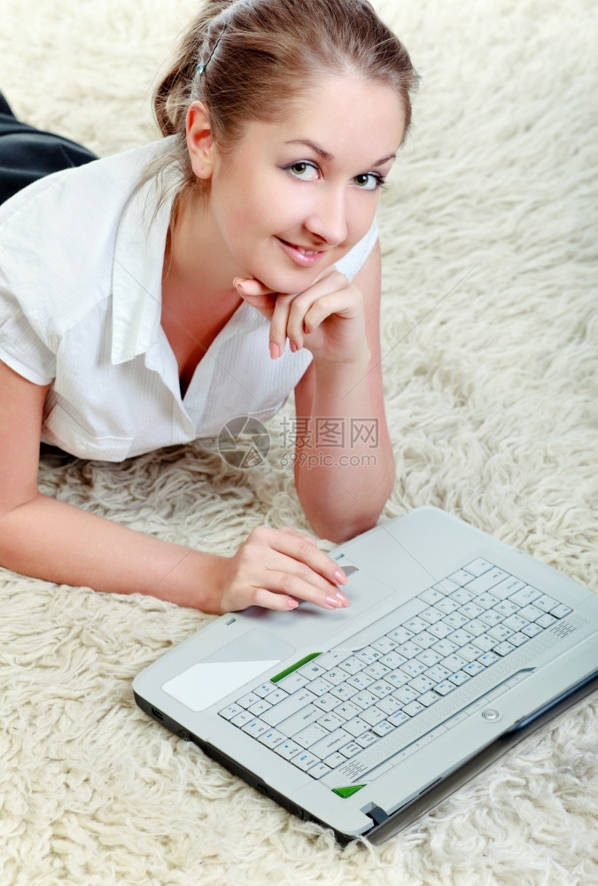 美丽的技术女商人妇用笔记本电脑躺在地板上图片