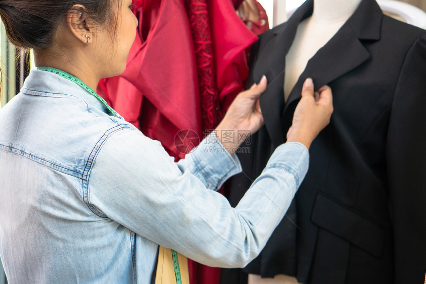 快乐的亚洲年轻女服装设计时师正在检查能否展厅完成一件西装和服这是成功的青年创业者在时装行中的概念措施陈列室在职的图片