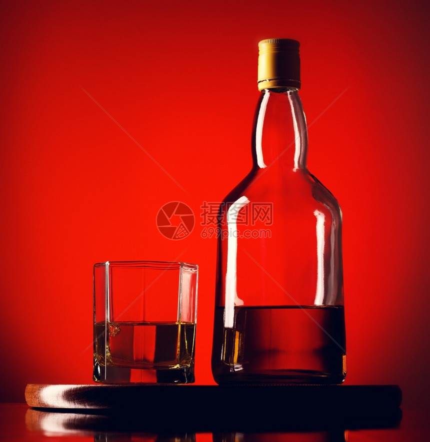 生活棕色的金威士忌酒杯玻璃和一瓶威士忌红底的图片
