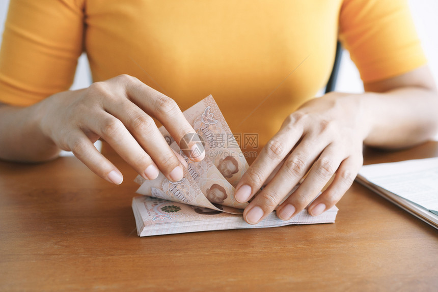 家中坐在桌边数钱的亚洲年轻女手握着亚洲年轻女手铢银行业税图片