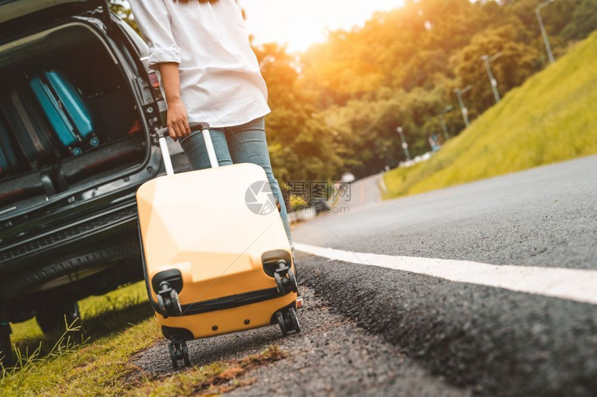 黄色手提箱拖着行李单独公路旅行装载到SUV车的后视图人们生活方式和度假概念自然夏季主题女孩冒险运输走夏天独自的图片