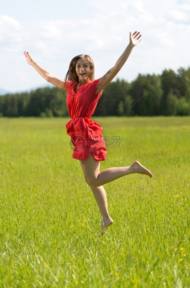 穿红裙子的年轻女孩在森林中游荡于田野夏天美丽的季节图片