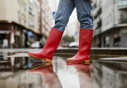 穿着雨靴站在路面积水中的人图片