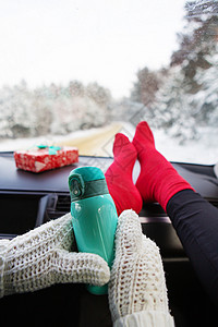 手脚寒冷脚方便的冬天坐在车里女孩拿着保温瓶以冬季森林旅行和冬季概念为背景冬天坐在车里女孩拿着保温瓶在冬季森林旅行的背景下和冬天概念路背景