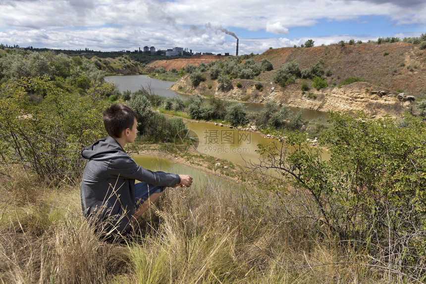一个少年在夏日看着废弃的采石场风景回收公司在地平线上一个少年在夏日看着废弃的采石场风景自由生红色的图片