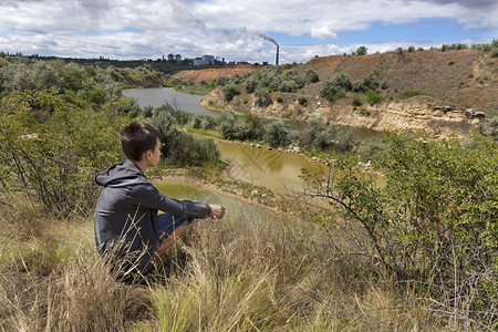一个少年在夏日看着废弃的采石场风景回收公司在地平线上一个少年在夏日看着废弃的采石场风景自由生红色的背景图片