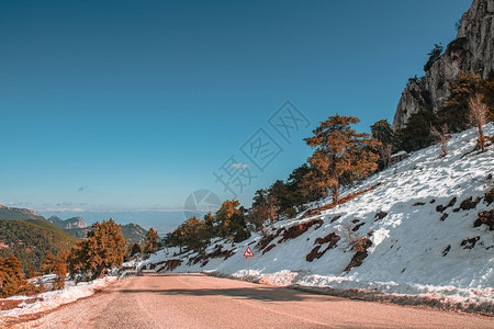 冷冻清净的沥青路山两侧都有雪冬天晴朗日阳光明平静的季节图片