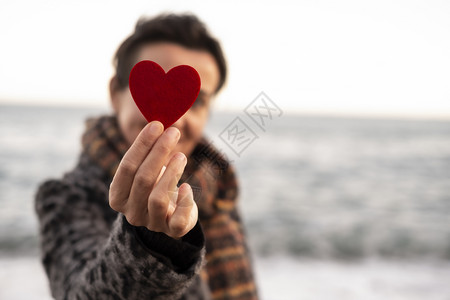 浪漫的女人手握着红心在海边的情人节概念上高架一种图片