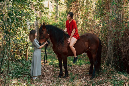 头发一种金女郎两个朋友聊天骑着马乘兜风穿过农村的乡间图片
