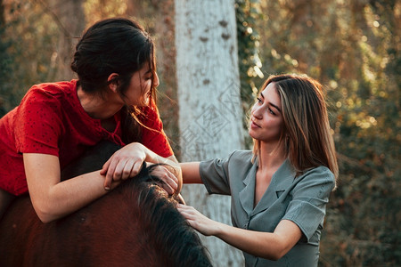 两个女朋友聊天骑着马乘兜风穿过农村的乡间爱好小路阳光图片
