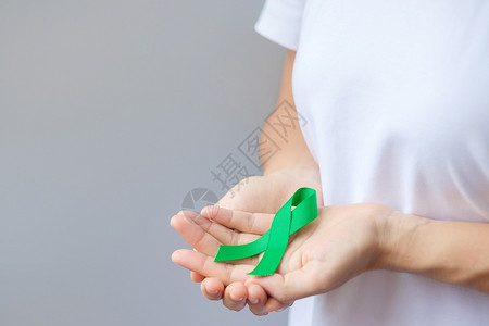 手拿绿丝带预防癌症概念背景图片