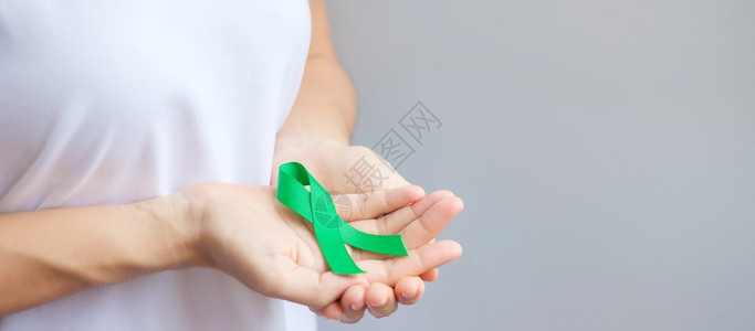 手拿绿丝带预防癌症概念背景图片