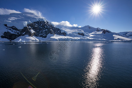 宽度山上有明亮的太阳和无云天空南极洲海边雪冰存储水图片