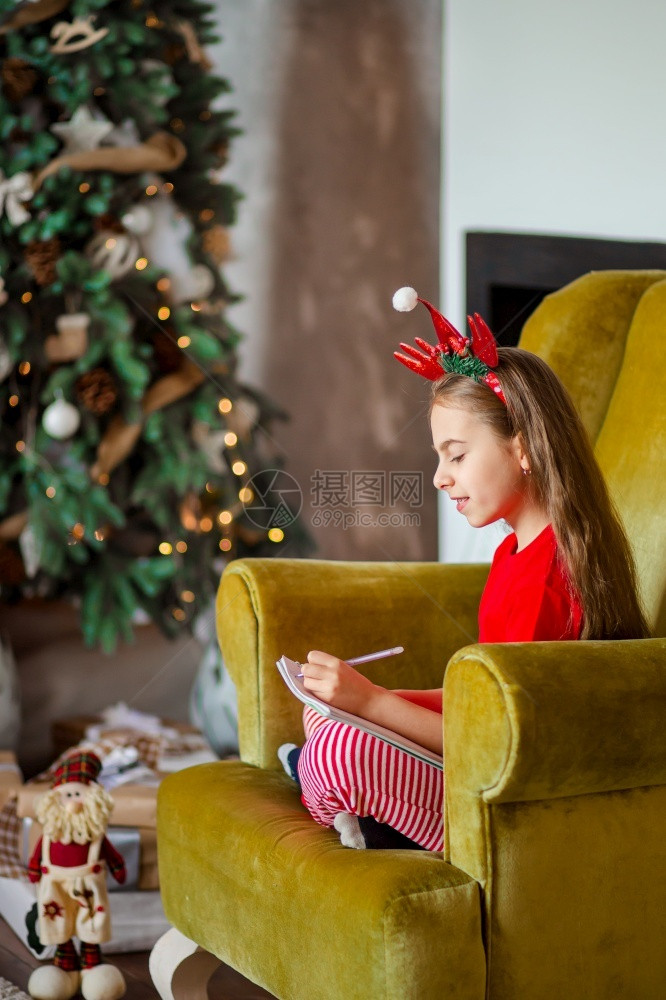 小女孩坐在沙发上给圣诞老人写信图片