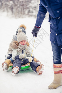 小女孩喜欢乘坐雪橇孩子们拉在户外玩雪手套爸帽子图片