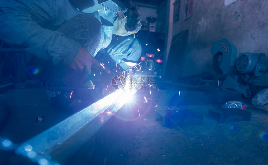 闪光作坊在工业场所与安全钢业合作的焊接工钢铁厂和焊接工钢铁厂一名男子佩戴焊接面罩和保护手套安全防行业图片