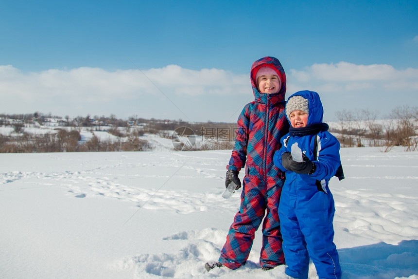 手套雪人欢迎快乐的兄妹在冬季散步公园里玩雪球图片