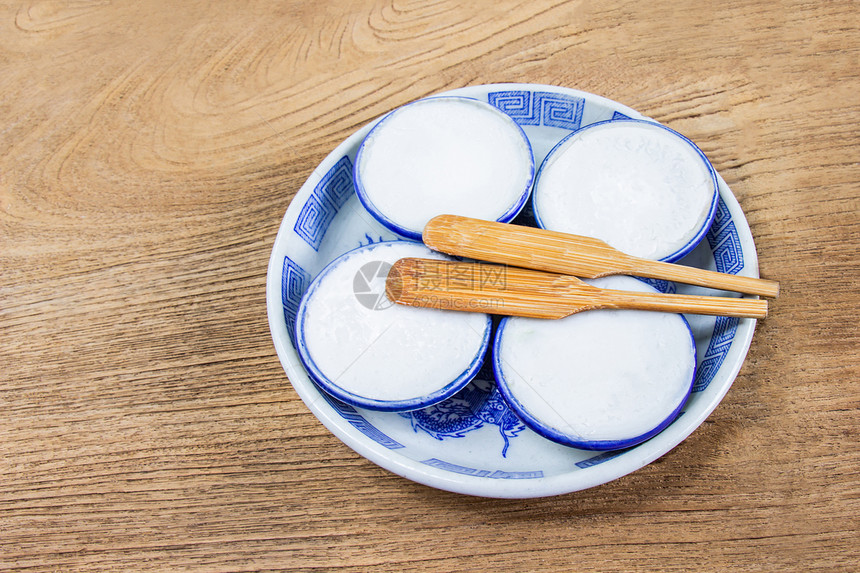 木制的陶瓷品泰国椰子牛奶碗是用面粉椰子奶和糖制成的泰式甜点把小型陶瓷杯放在木制地板上传统图片