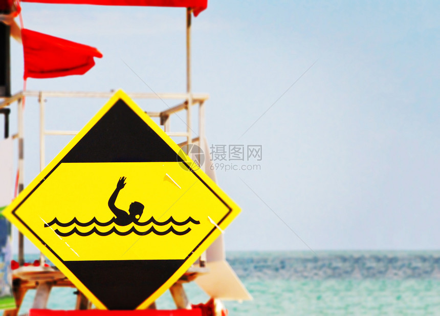 淹蓝色的海滨黄危险信号显示在狂海波浪中溺水游泳的潜员图片