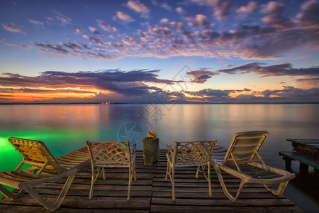空的海岸夏天甲板椅子和木制码头的椅子等待海边日出图片
