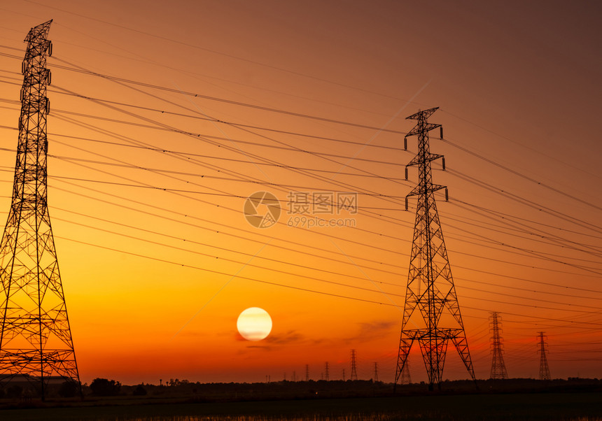 电压高的柱和线缆有日落天空电杆极和能源概念高压电网塔配有铁线电缆的压网塔日落时美丽的大太阳与红云天空橙日出红色图片