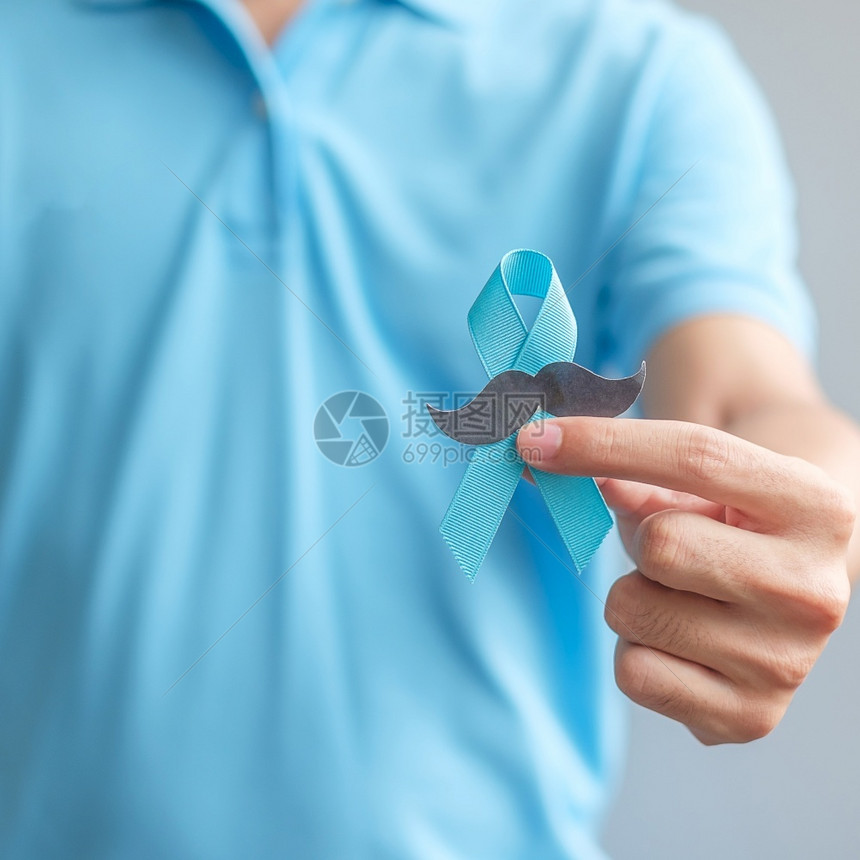 男子拿着蓝丝带预防癌症概念图片