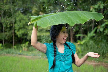 模型漂亮的农场在绿花园背景下雨时一位年轻亚洲女身着香蕉叶的黑头发肖像图片
