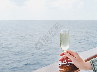 船栏杆在蓝海浪背景下游轮露天甲板上举着美丽玻璃的时装妇女侧观特近休闲和旅行概念女在甲板上举着玻璃女士在甲板上举杯鸡尾酒日落人们背景