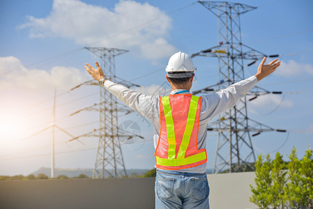 极电动工程师站在手举起天高电压杆背景的手顶上保持商业图片